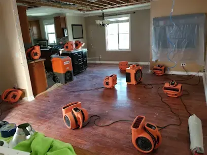 Orange air movers drying a hardwood floor with walls opened in a Palmdale home
