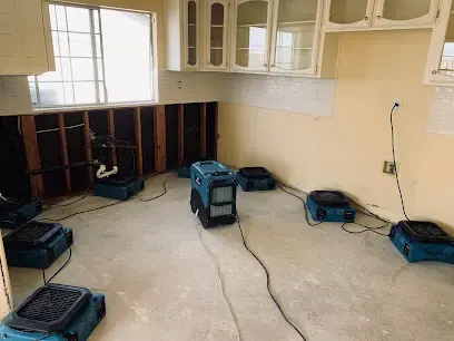 Air movers and a dehumidifier drying a kitchen with the lower drywall removed in Palmdale