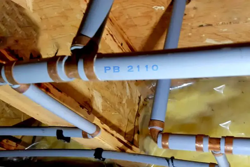 Gray polybutylene PB 2110 supply lines with copper crimp rings in a Palmdale attic