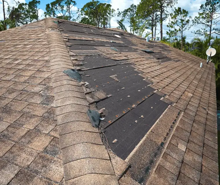 Wind-stripped shingles exposing roof underlayment after a storm near Palmdale